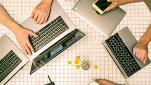 Vista superior de equipe colaborando com notebooks, celulares e anotações em um escritório