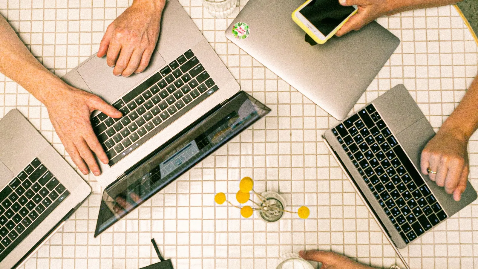 Vista superior de equipe colaborando com notebooks, celulares e anotações em um escritório
