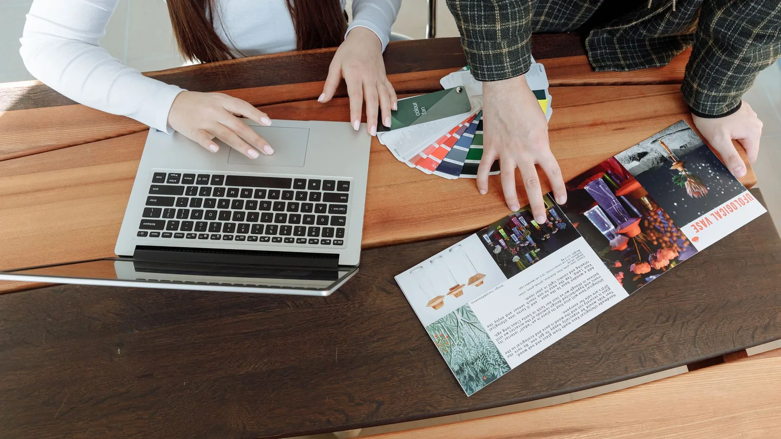 Dois colegas trabalhando em um projeto de design com notebook e guias de cores
