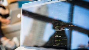 Notebook exibindo código de programação com reflexo na tela