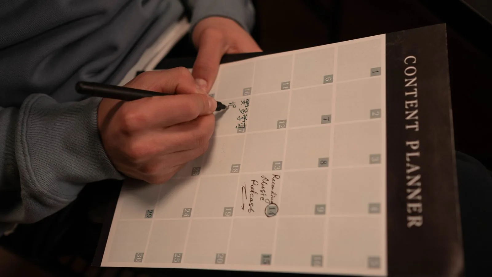 Modelo de contrato de gestão de redes sociais 1 Planejador de conteúdo mensal sendo preenchido à mão com o calendário de postagens
