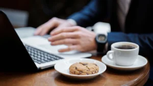 Notebook em uso ao lado de xícara de café e biscoito