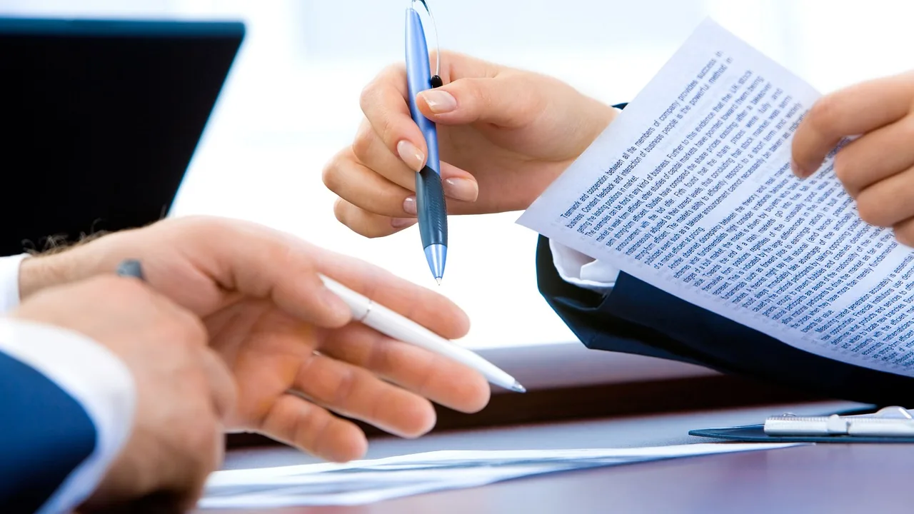 Mãos com caneta e contrato impresso durante reunião de negócios