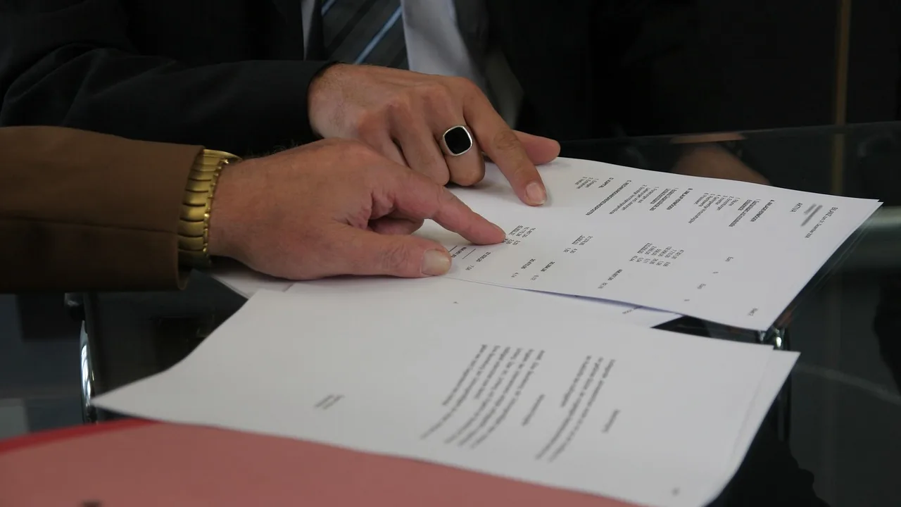 Mãos apontando cláusulas em contrato impresso sobre a mesa, representando a negociação entre agência e influenciador