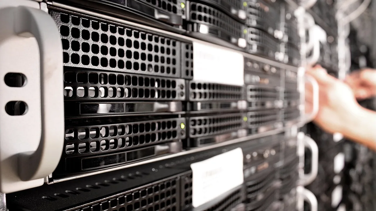Mão manuseando servidores em rack de data center, representando a infraestrutura que hospeda o agente de IA e os dados
