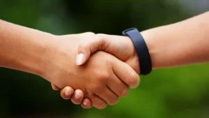 Aperto de mão entre duas pessoas ao ar livre, representando o acordo de prestação de serviços