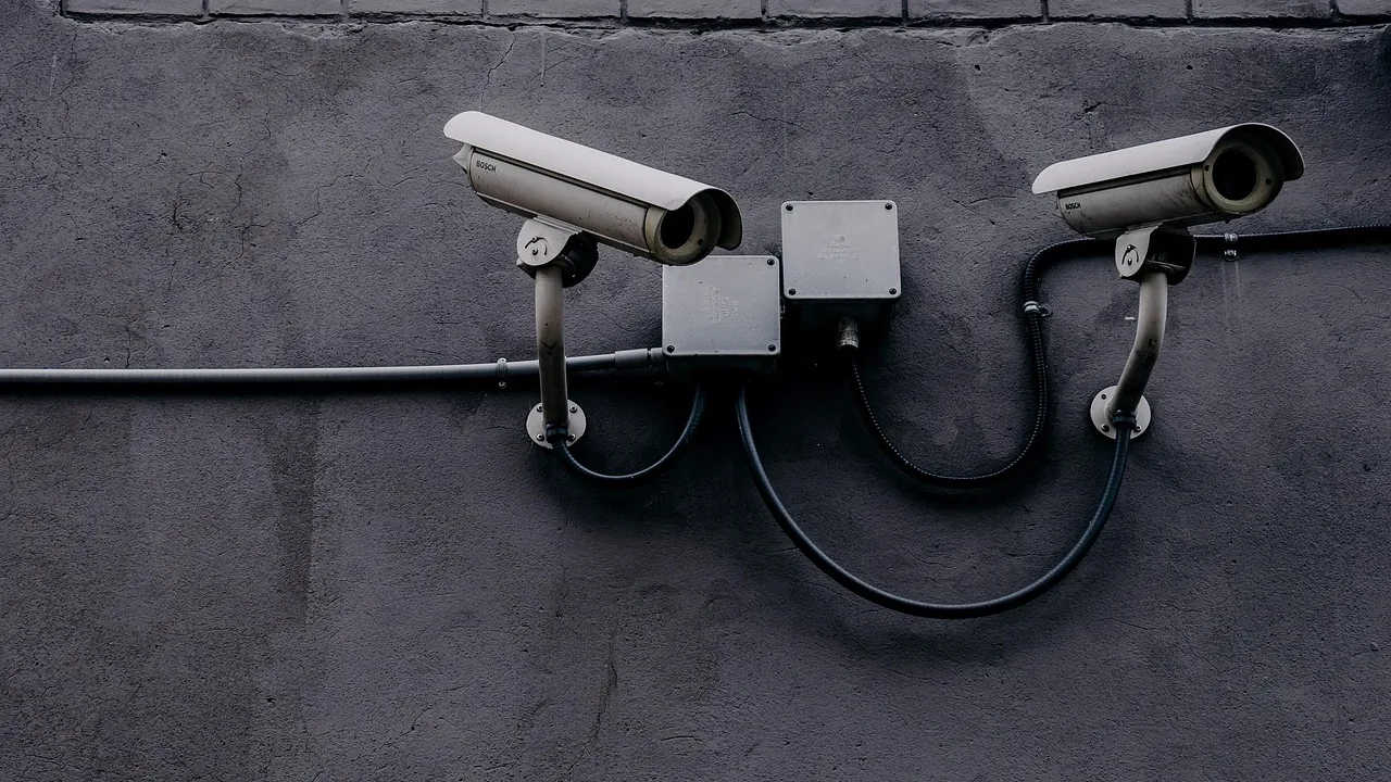 Duas câmeras de vigilância presas a uma parede escura, representando os limites do monitoramento e a privacidade