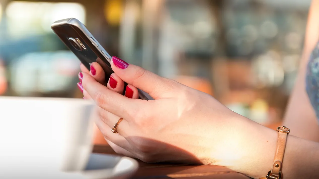 O que é o direito à privacidade e por que ele importa 1 Mãos segurando um celular em uma mesa de café, representando a vida privada no uso diário da tecnologia