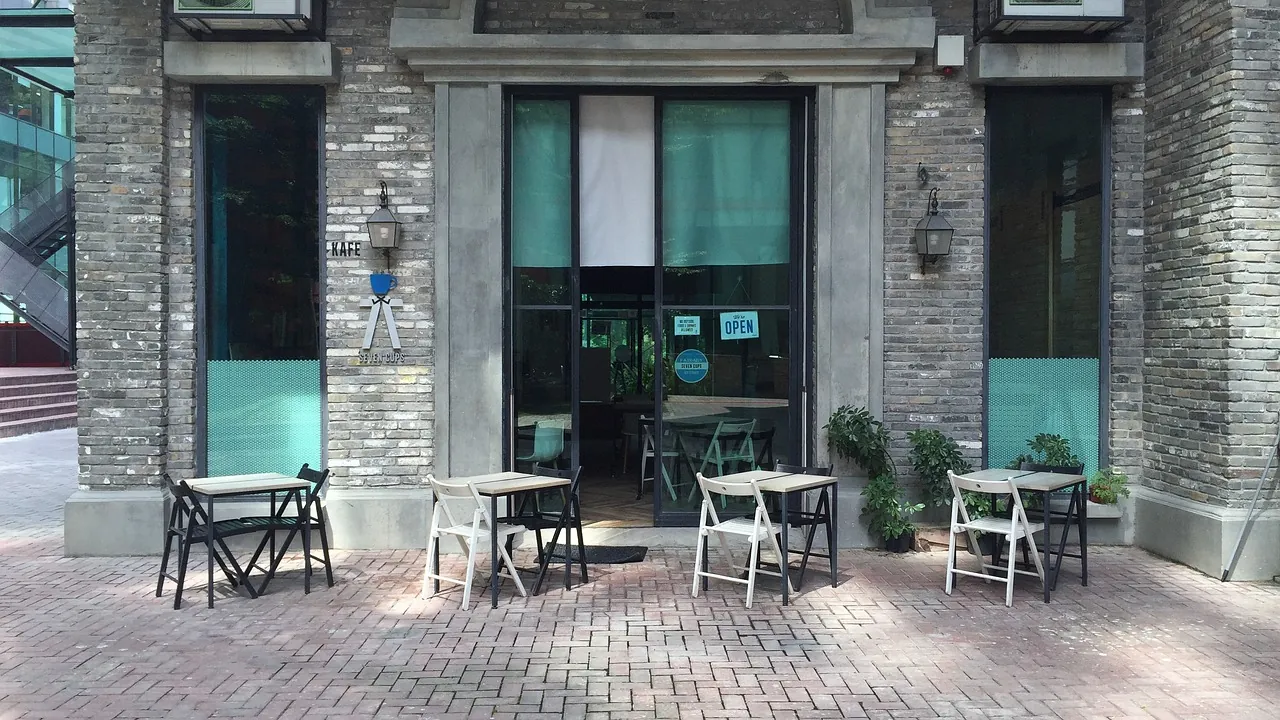 Fachada de cafeteria com mesas na calçada, representando o pequeno negócio que precisa proteger a marca