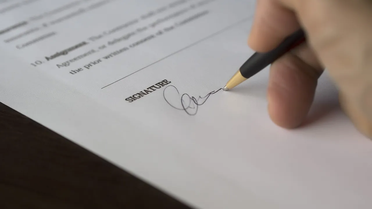 Quando o freelancer passa a ter vínculo de emprego? 2 Mão assinando um contrato com caneta, representando a formalização do contrato de trabalho intermitente