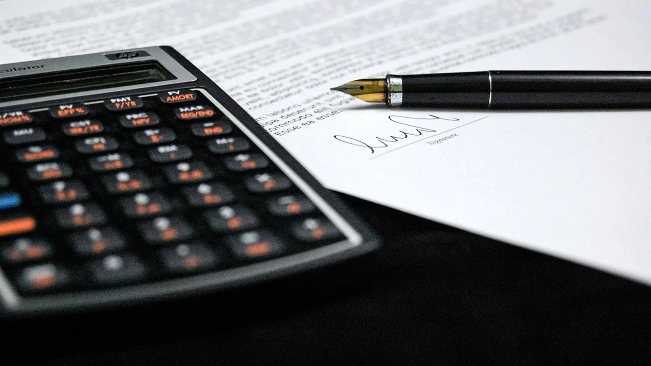 Calculadora e caneta sobre contrato assinado, representando preço e pagamento