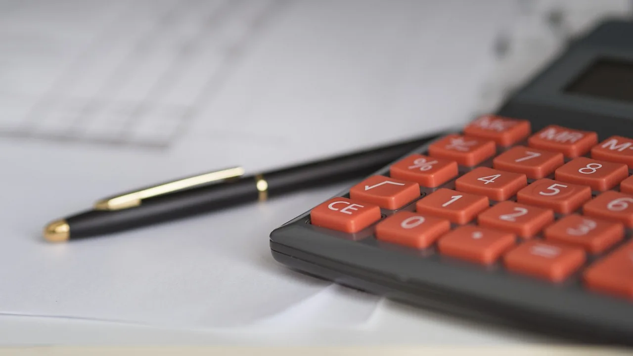Modelo de Petição de Rescisão Contratual por Falta de Pagamento. 1 Caneta e calculadora sobre documentos, representando o cálculo da dívida e dos encargos