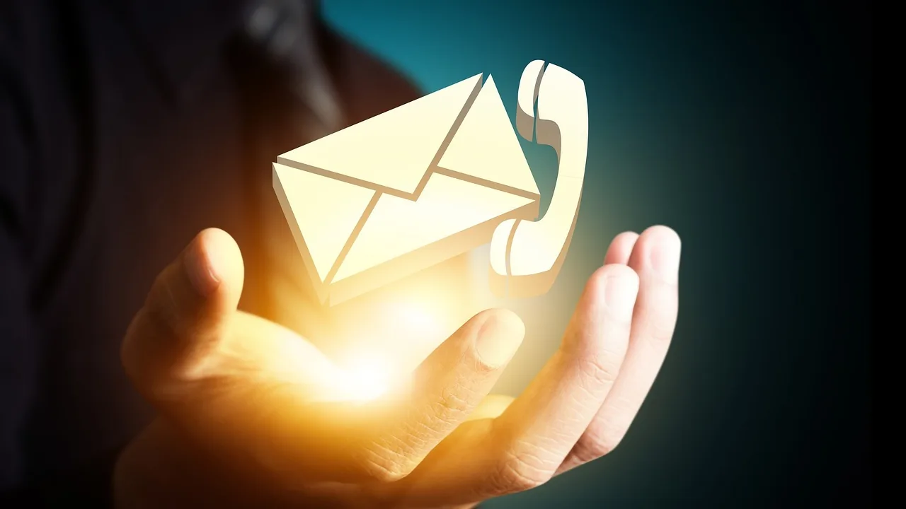 Mão segurando ícones luminosos de envelope e telefone, representando os canais digitais de atendimento