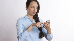 Mulher de camisa social usando o celular, representando o uso das redes sociais por trabalhadores