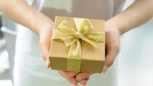 Mãos segurando caixa de presente com laço dourado, representando o prêmio de um sorteio no Instagram
